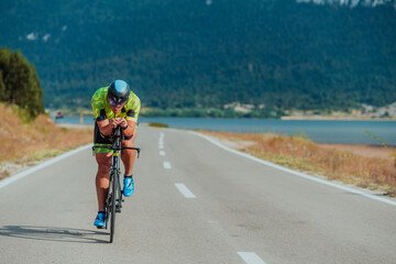 Close up photo of an active triathlete in sportswear and with a protective helmet riding a bicycle....