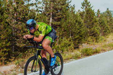 Fototapeta premium Full length portrait of an active triathlete in sportswear and with a protective helmet riding a bicycle. Selective focus 