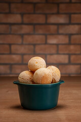 Cheese breads in a green ramekin on wooden table and bricks wall background.