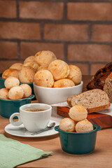 Cheese breads in a green ramekin with a cup of coffee on wooden table and bricks wall background.