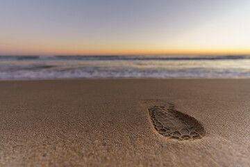 Fototapeta na wymiar Beautiful sunset on a quiet sandy beach with a footprint