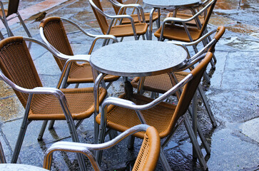 Two smart sparrows are hiding under the metal table from the rain. Salamanca, Spain