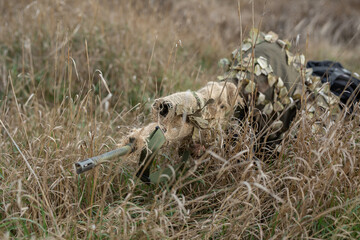 Sniper in camouflage suit in the grass.
