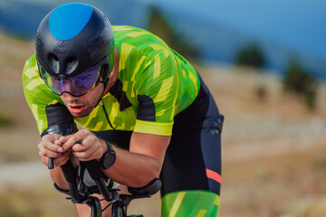 Close up photo of an active triathlete in sportswear and with a protective helmet riding a bicycle....