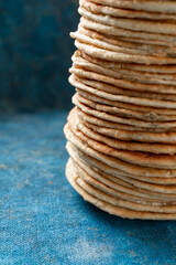 Flatbread lavash, chapati, naan, heap of tortilla on a blue background Homemade flatbread stacked.