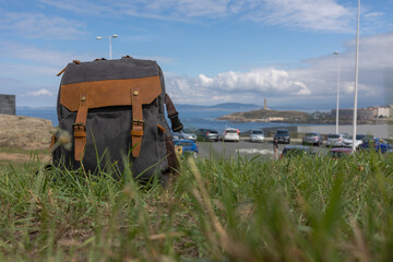 Fototapeta premium A travel bag stands in the grass against the blue sky and ocean.