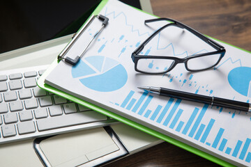 Pen, eyeglasses, graphs on the computer keyboard.