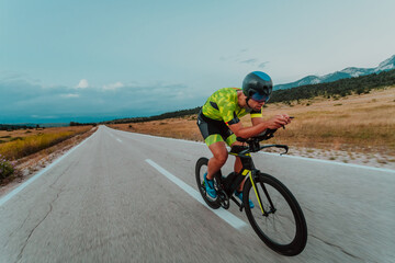 Full length portrait of an active triathlete in sportswear and with a protective helmet riding a...