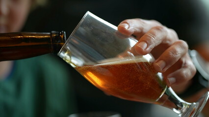 Closeup hand serving beer into glass. Man pouring alcoholic beverage. fresh cold alcohol drink. Pale ale