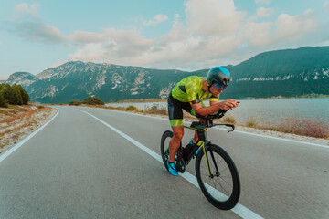Full length portrait of an active triathlete in sportswear and with a protective helmet riding a...