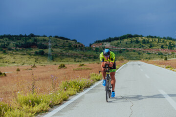 Full length portrait of an active triathlete in sportswear and with a protective helmet riding a...