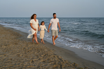 Fototapeta na wymiar couple with pregnant woman walking on the beach