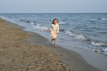 little girl dressed in white running on the beach