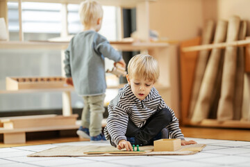 Children at montessori kindergarten are playing with educational toys and learning through the game.