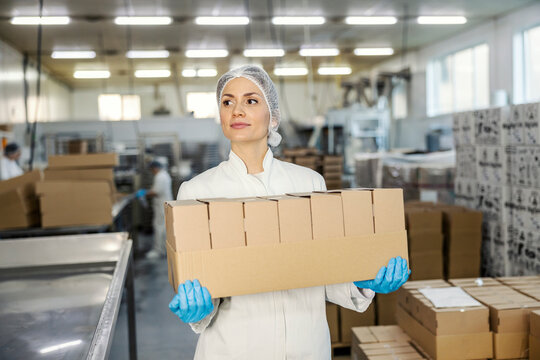 A food food factory worker is carrying boxes in facility. - Powered by Adobe