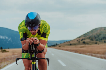 Close up photo of an active triathlete in sportswear and with a protective helmet riding a bicycle....