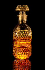 Golden alcoholic drink in decanter, bottle and glass