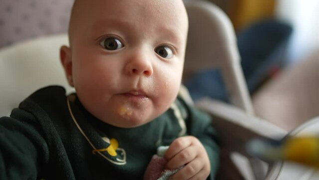 baby newborn eats. dirty mess baby boy eating vegetables. baby son eats on a feeding chair dirty face. naughty dirty babe indulges while feeding. happy kid dream family weaning indoors concept