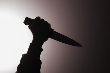 Close up of mysterious man wearing black hoodie holding a knife to stab someone. Crimes and criminality concept