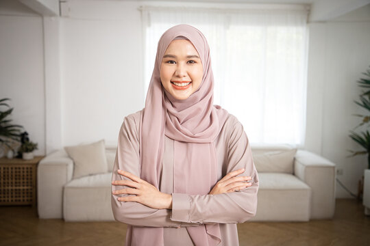 Woman in traditional Muslim clothing, Smiling. Beautiful woman headshot looking at camera and wearing a hijab in the living room. Asian culture and Society