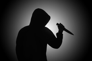 Mysterious man wearing black hoodie holding a knife to stab someone. Crimes and criminality concept - obrazy, fototapety, plakaty