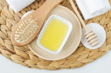 Small white bowl with honey and wooden hairbrush. Natural skin care, homemade spa and beauty treatment recipe. Top view.