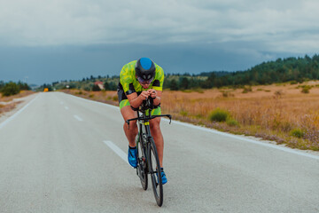 Full length portrait of an active triathlete in sportswear and with a protective helmet riding a...