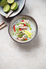 Bowl of traditional vietnamese Pho Ga soup on a beige stone background, vertical shot with copy...