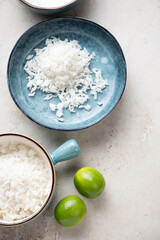 White rice in turquoise bowls on a light-beige stone background, vertical shot with space, above view