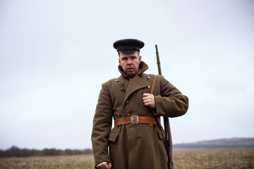 a brave soldier of the first world war holds a gun on his shoulder and looks at the camera. retro...