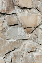 A fragment of an old wall. Bumpy stone surface. Stone background, a vertical photo.
