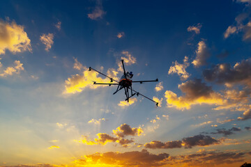 Drone flying in the air. Sunrise background.