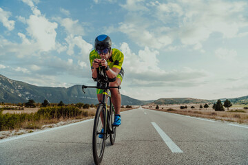 Fototapeta na wymiar Full length portrait of an active triathlete in sportswear and with a protective helmet riding a bicycle. Selective focus 