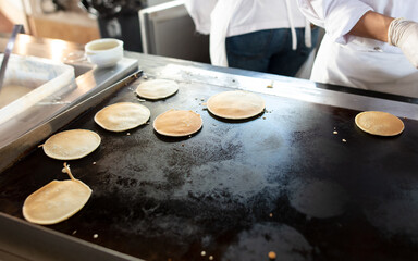 The cook is frying pancakes in the kitchen.