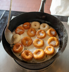 Donuts are fried in a frying pan in oil.