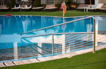 Metal stairs to the blue water of the pool.