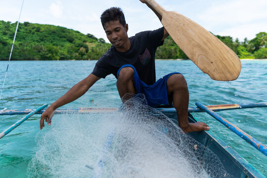 young filipino fisherman preparing fishing net on his boat, philippines islands, real people, lifestyle