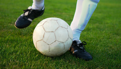 legs of a soccer player with ball in sunset on soccer field