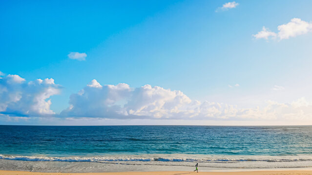 Runner run along the coast of ocean at sunrise - Powered by Adobe