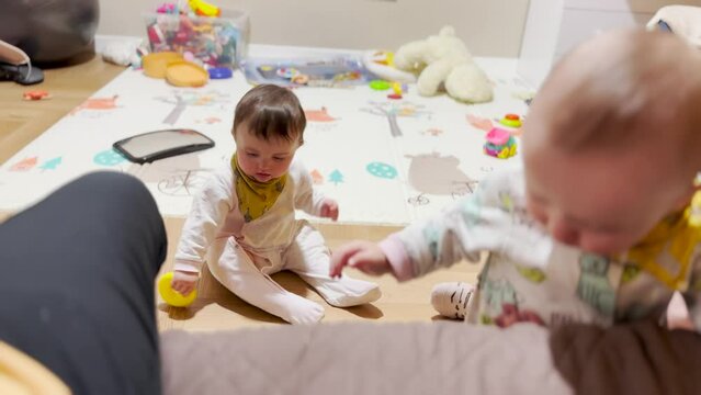 baby toddlers play in kindergarten on the floor. the teacher sings from the baby bottle baby in kindergarten. baby kids playing on the sofa in kindergarten lifestyle