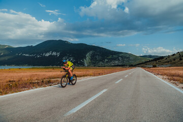 Full length portrait of an active triathlete in sportswear and with a protective helmet riding a...