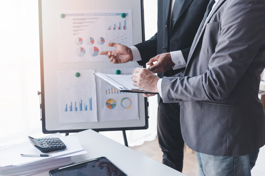 Finance and investment concept, Businessman present business finance investment plan with his partner, Investor colleagues discussing new investment plan by financial graph data on office table  - Powered by Adobe