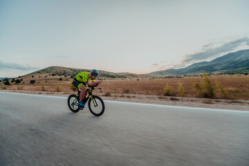 Full length portrait of an active triathlete in sportswear and with a protective helmet riding a...
