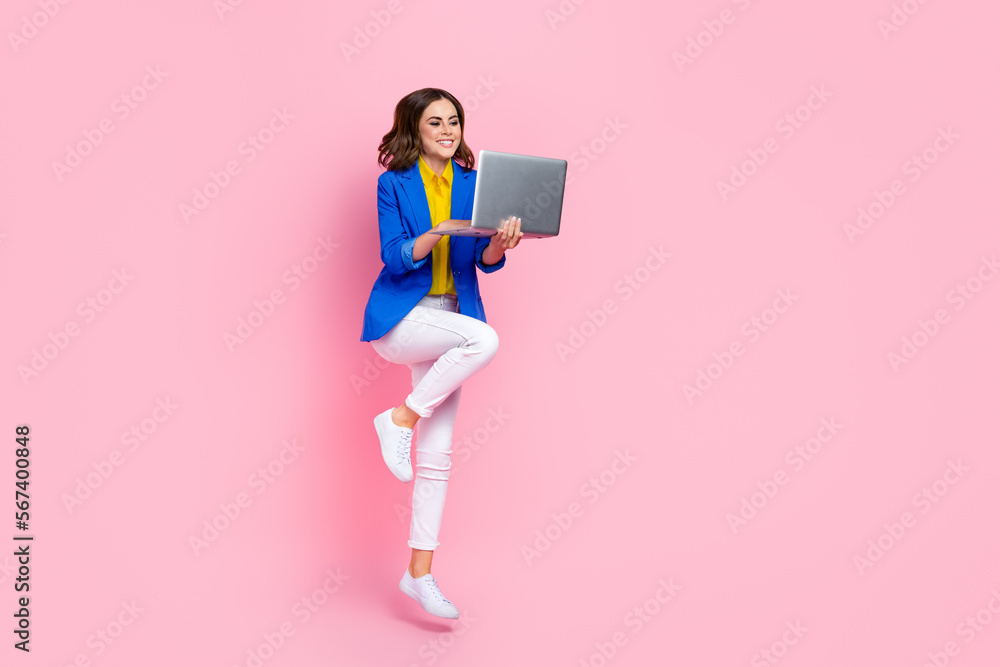 Poster full length portrait of cheerful excited person jumping use netbook empty space isolated on pink col