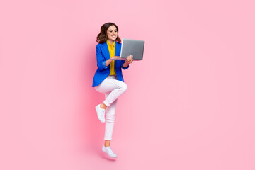 Full length portrait of cheerful excited person jumping use netbook empty space isolated on pink color background