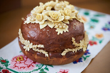Ukrainian traditional holiday bread - loaf. Ukrainian decorated fresh loaf with salt lies on the table, next to the embroidered towel. Ukrainian wedding traditions.