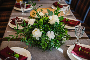 Decor details. Festive table with tablecloth decorated with composition of flowers and greenery in the banquet hall. Table for guests in banquet area on party in restaurant. Wedding setup. Top view.