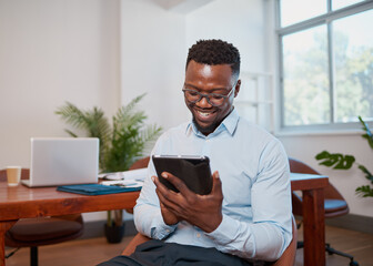 Young Black businessman uses digital tablet smiling in conference room office