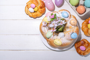 Easter wreath bread, traditional Easter holiday baking, sweet bun cakes with colorful Easter eggs, on brunch holiday decorated table copy space