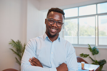 Close up Black businessman poses with arms folded in office